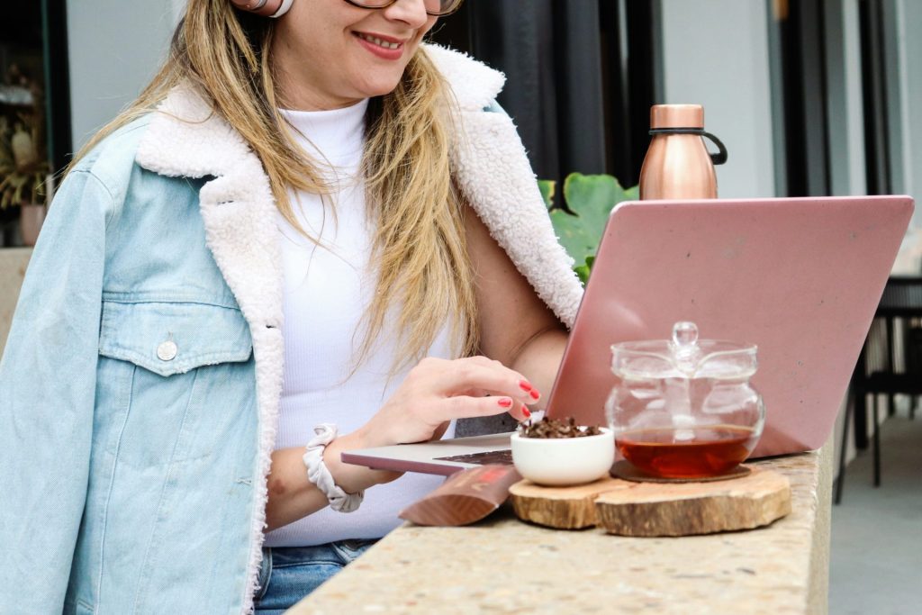 Frau in weißer Strickjacke hält eine silberne Gabel und ein Glas Getränk