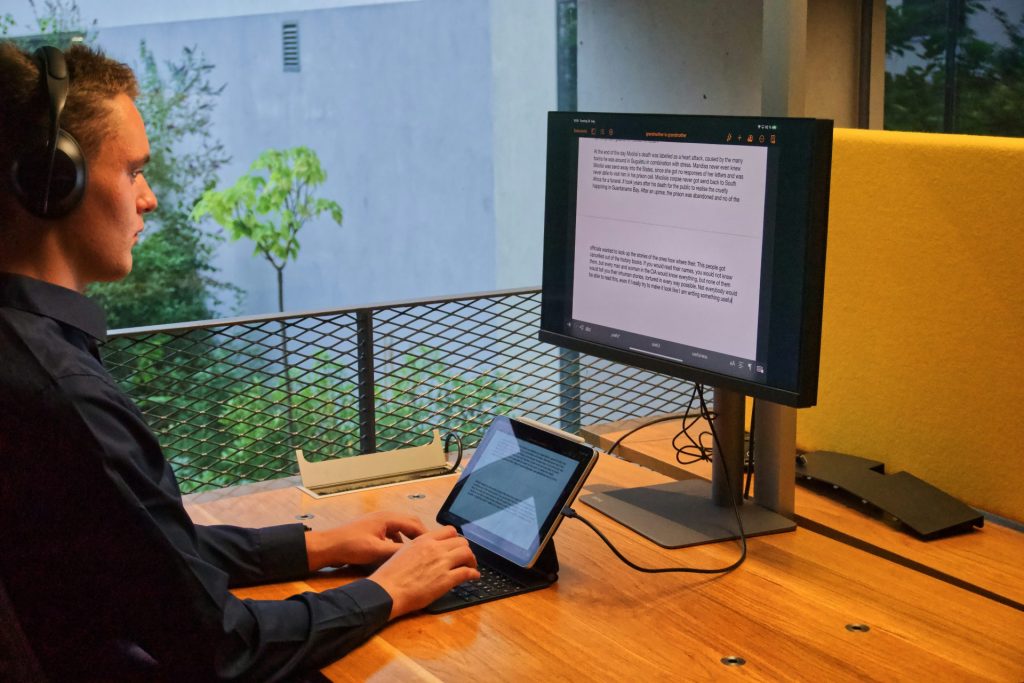 Persona con camisa negra de manga larga usando un MacBook Pro sobre una mesa de madera marrón